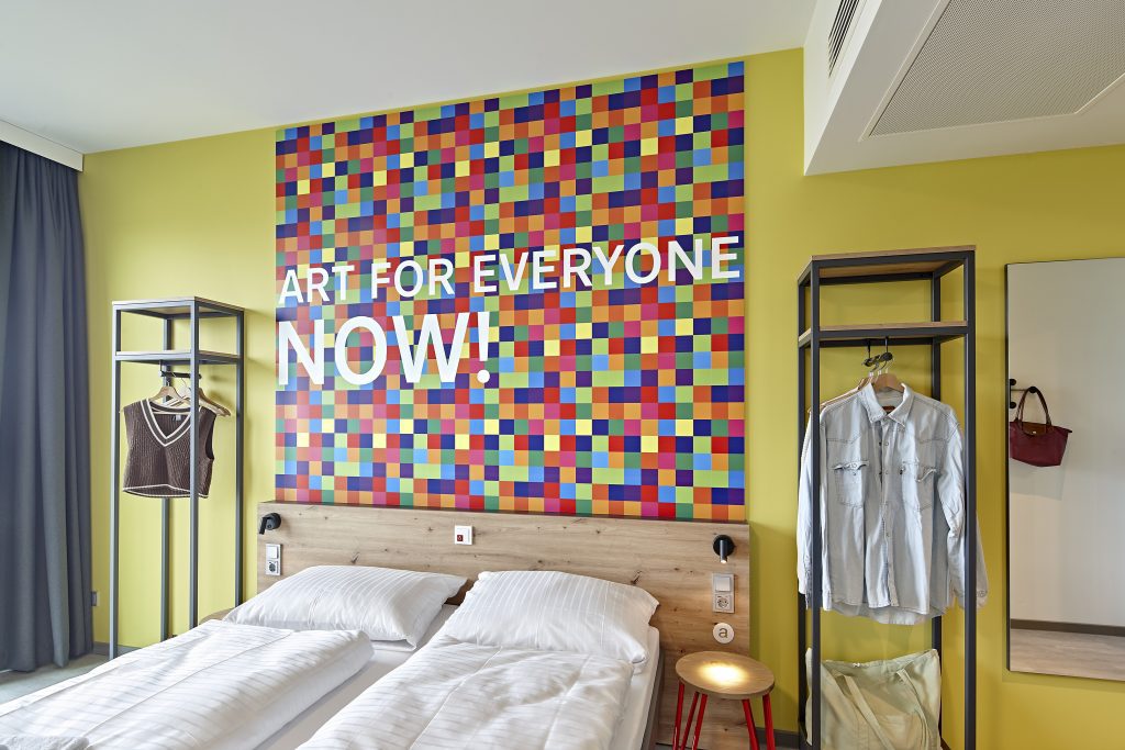 Colorful hotel room with Art for Everyone wall mural and clothing racks