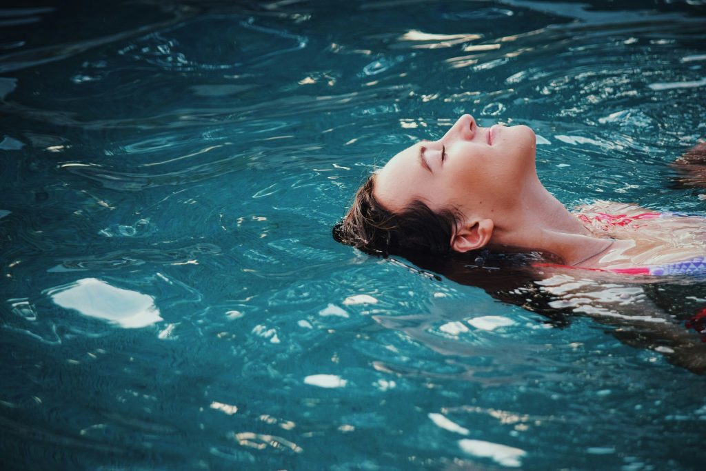 Was du an einem Sonntag in Berlin machen kannst: Eine Frau treibt mit geschlossenen Augen auf dem Rücken im Pool