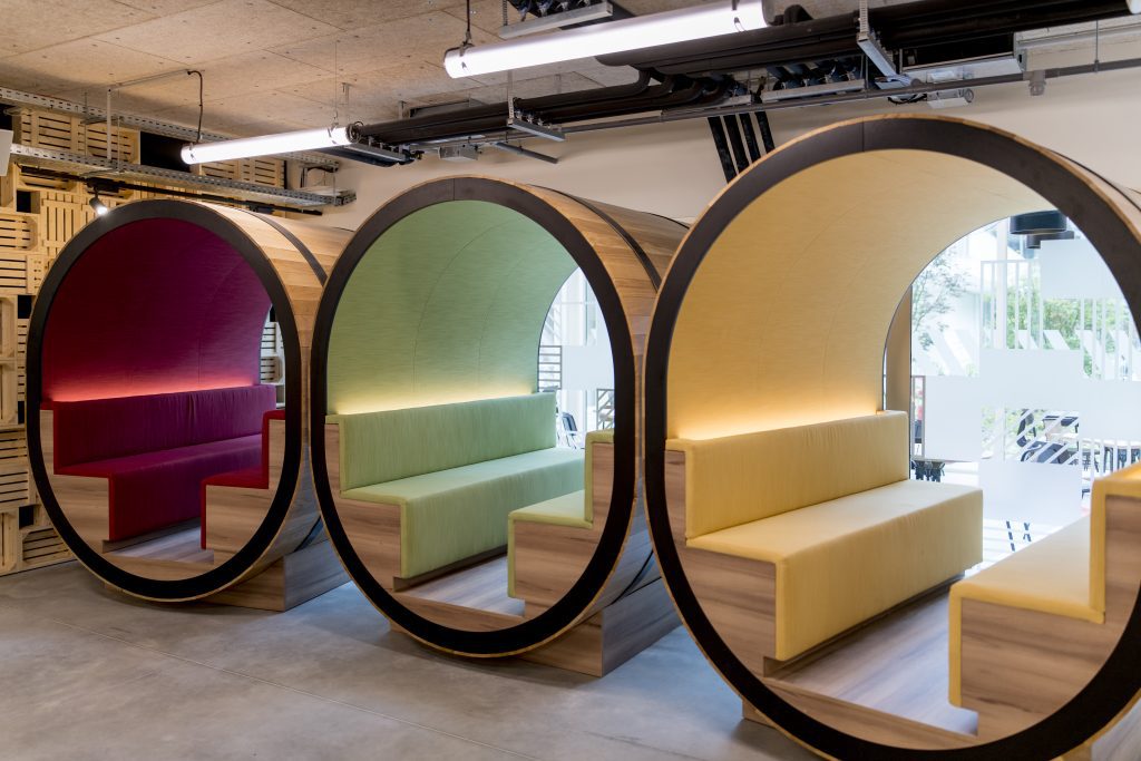 Three round barrel-shaped lounge seats in red, green, and yellow