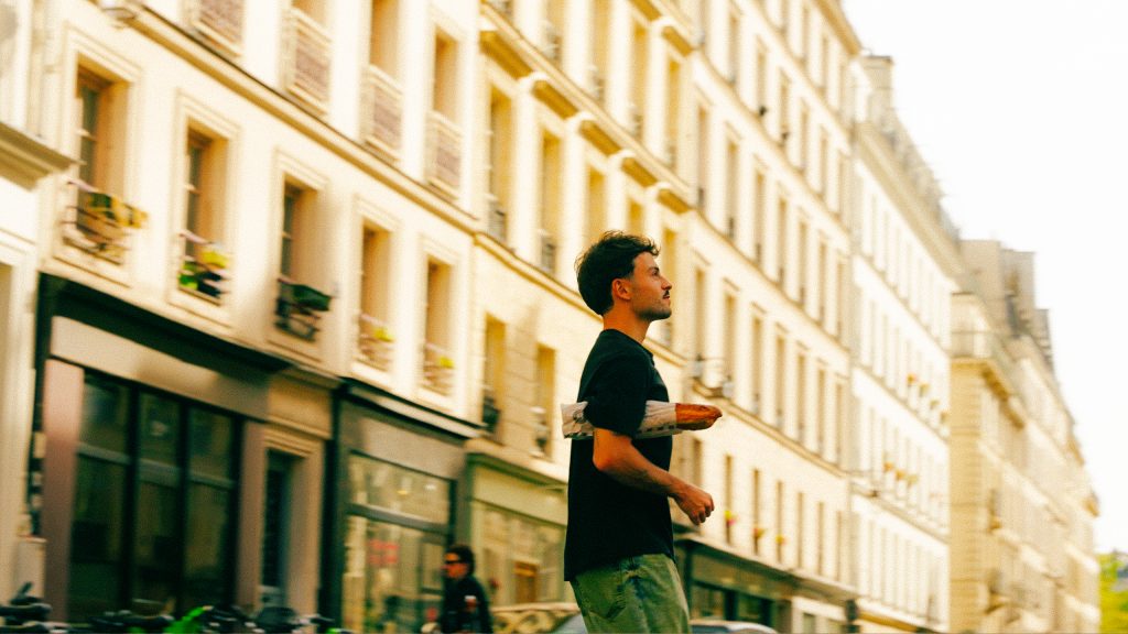 Backpacking Frankreich kleinem Budget: Mann mit Baguette auf einer typischen Pariser Straße, nahe MEININGER Hotel