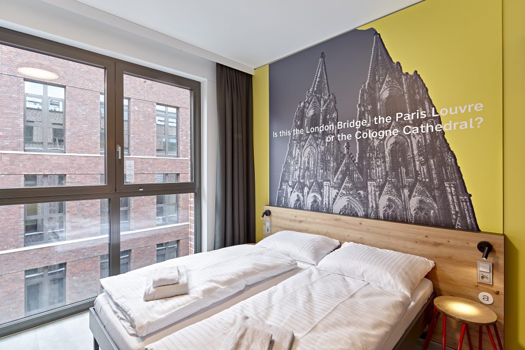 Twin room with a Cologne Cathedral wall mural at MEININGER Köln West