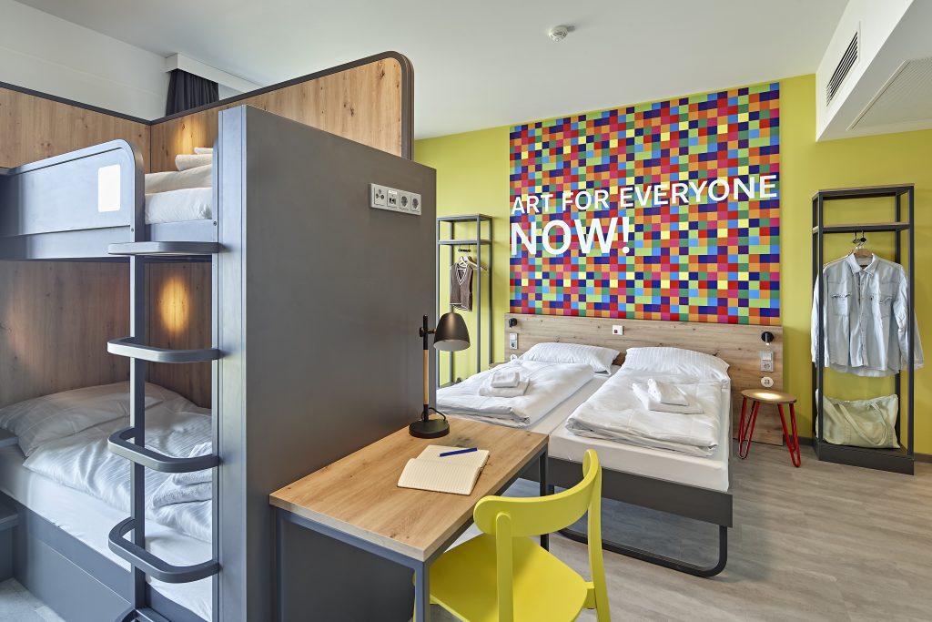 Family room with bunk beds, desk and colourful wall art, MEININGER Köln West