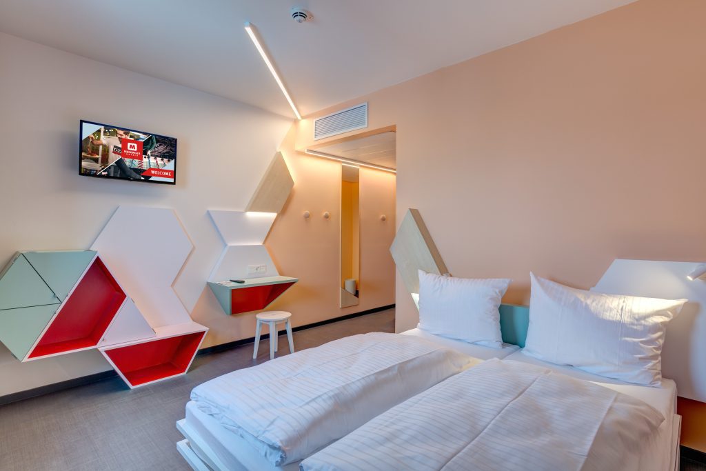 Colorful double room with playful geometric wall design at MEININGER Hotel Heidelberg Hauptbahnhof