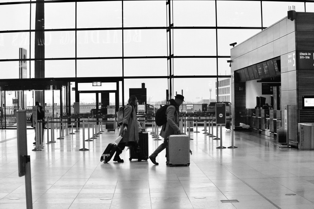 Luggage storage Berlin: Travelers pulling suitcases at Berlin Airport (BER) terminal, black and white