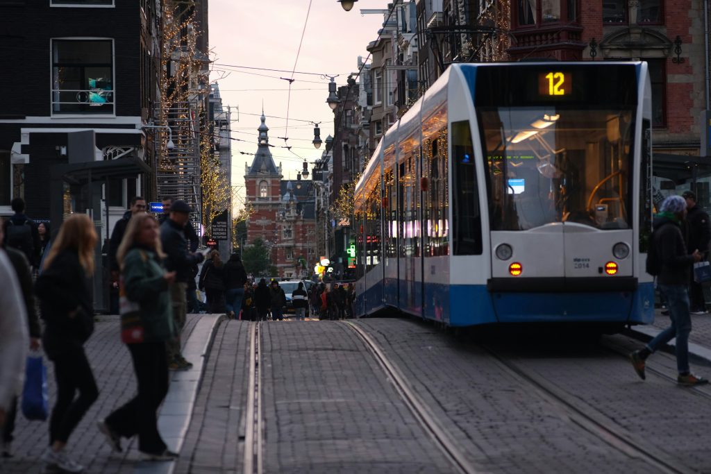 Amsterdam street at dusk with people and a tram