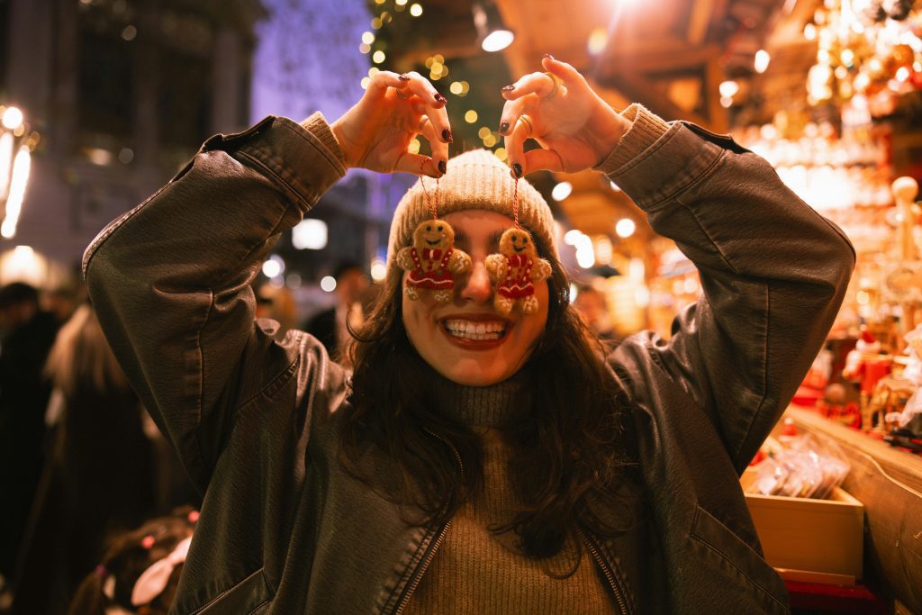 Cologne Christmas markets: Woman holding gingerbread ornaments over her eyes at a Christmas market