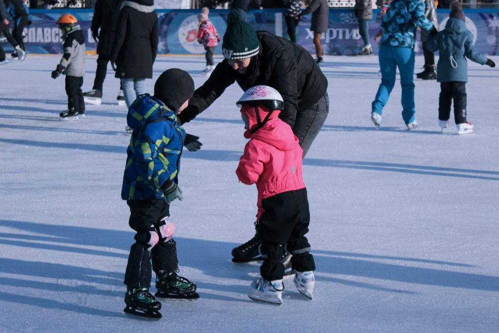 Cologne Christmas markets: Mother helping two kids learn to ice skate at a Christmas market rink in Cologne