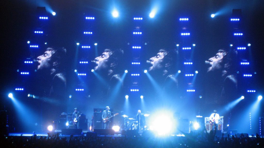 Oasis tour 2027: Oasis live on stage with blue lights and big screens ahead of the 2027 tour