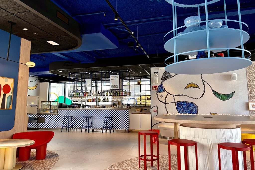 Colorful hotel bar with checkered tiles, red stools and mosaic wall art