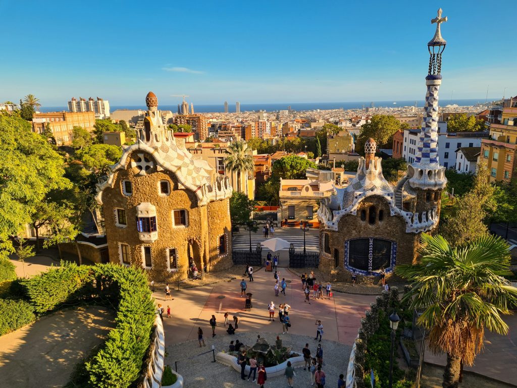 School trip to Barcelona: Mosaic gatehouse and plaza at Park Güell, with Barcelona's skyline behind it
