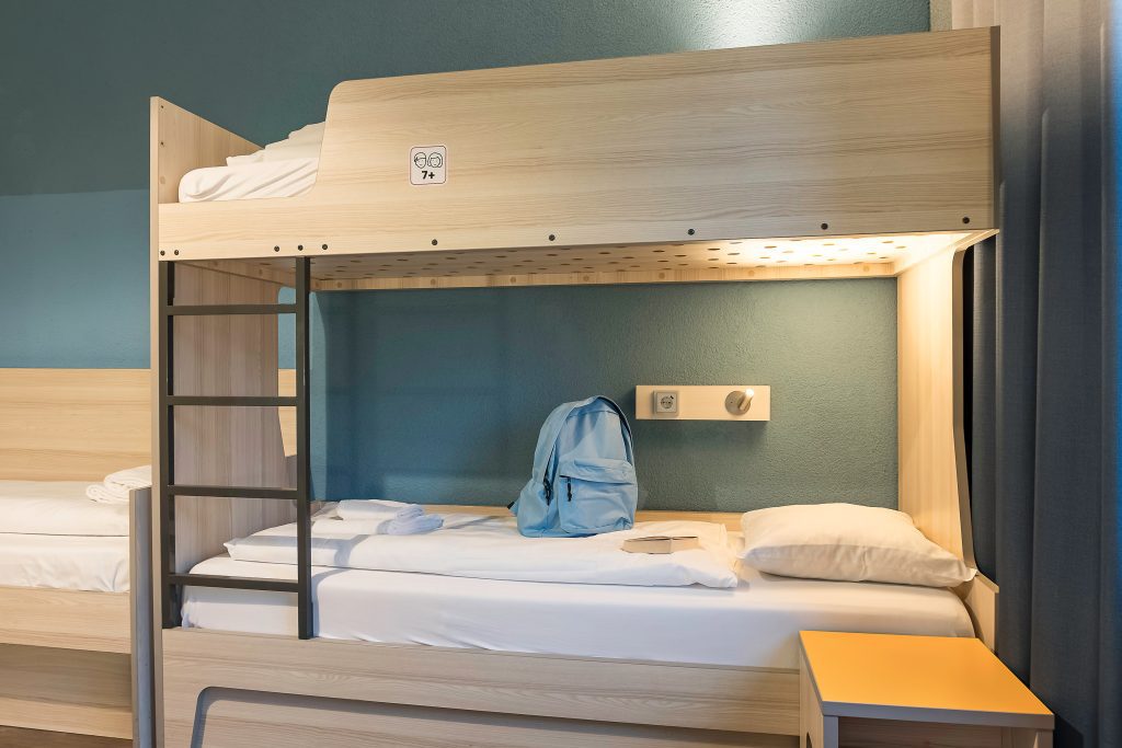Wooden bunk bed with a blue backpack on the mattress