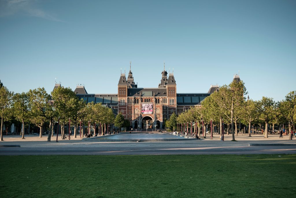 Luggage storage Amsterdam: Red-brick Rijksmuseum seen across the lawn of Museumplein in Amsterdam at sunset