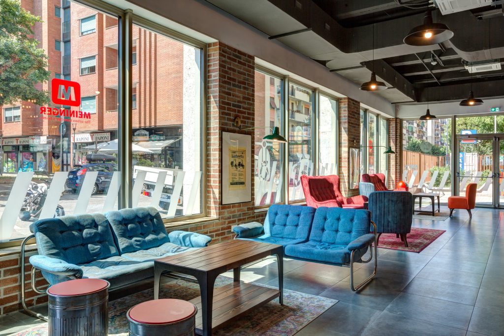 Retro blue sofas and red armchairs in the sunny MEININGER Milan lobby