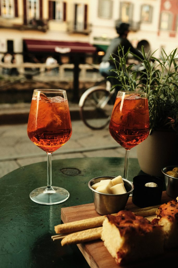 Two spritz glasses with cheese, focaccia and breadsticks on a Milan bar table
