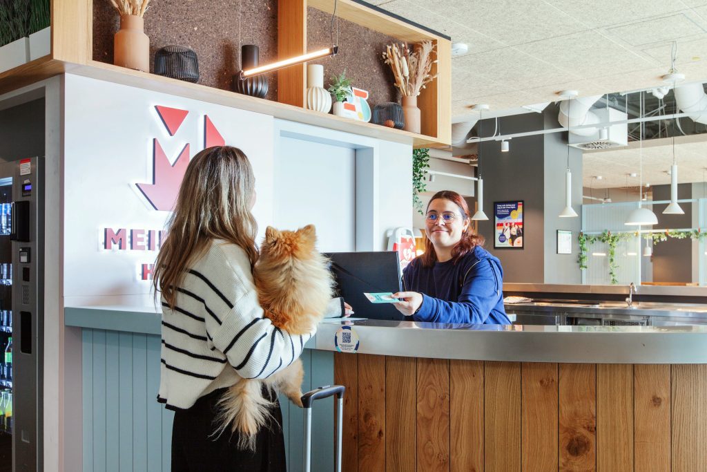 Woman with a cat chatting to the friendly receptionist at MEININGER Hotels
