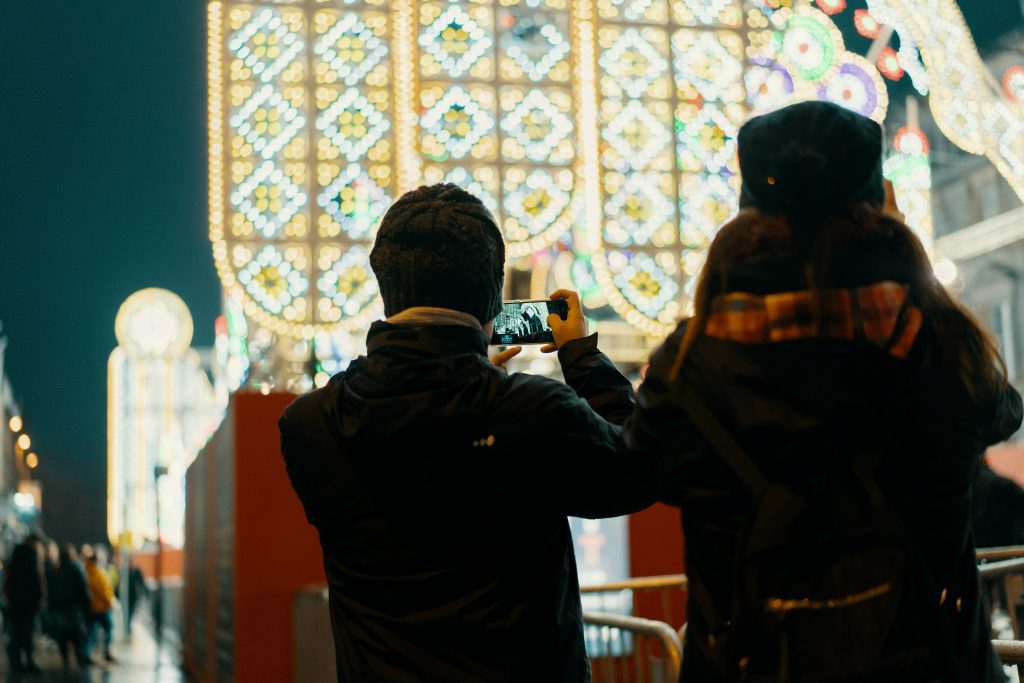 Two people from the back taking photos of a Christmas light installation