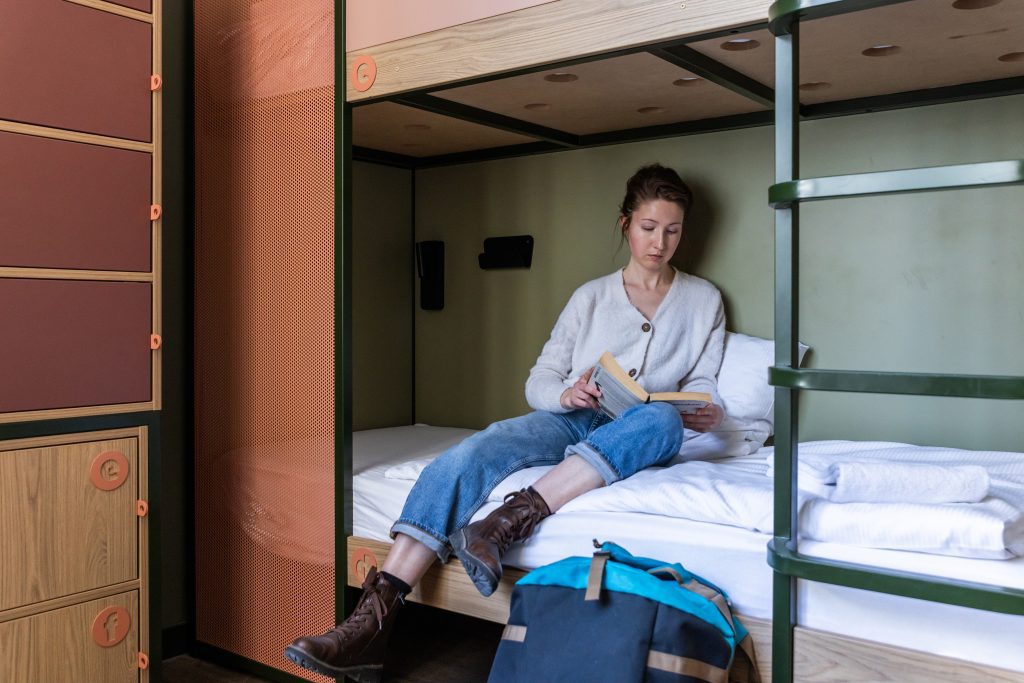 Solo traveller reading on a bunk bed with lockers 