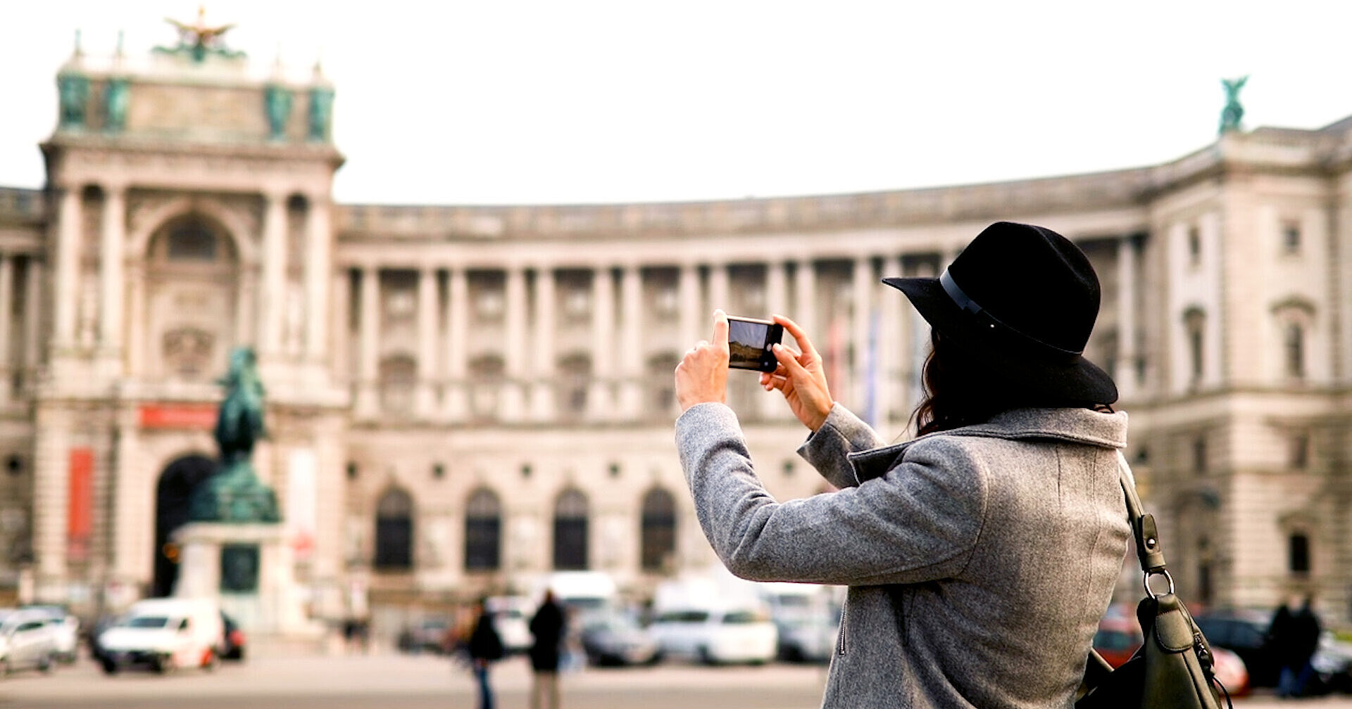 Traveler photographing Vienna’s Hofburg Palace, a historic landmark near MEININGER Hotels.