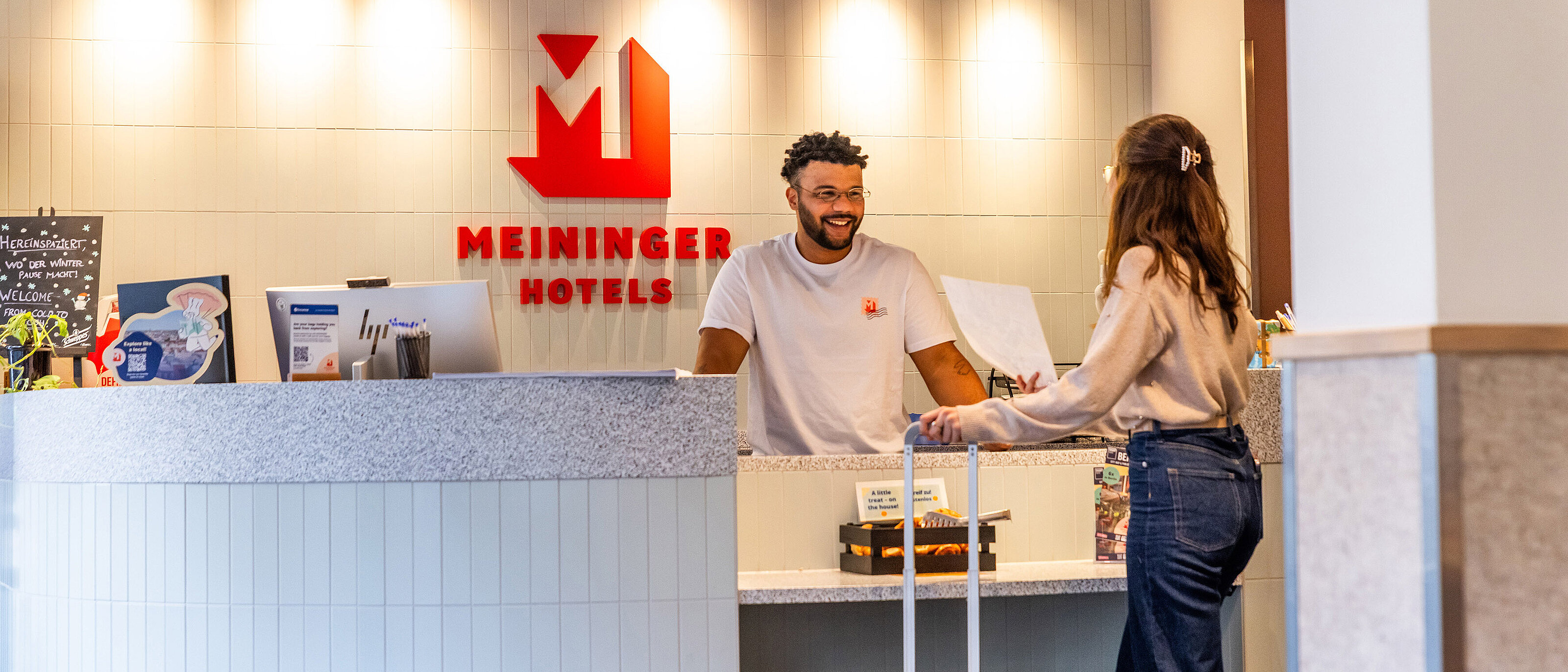 Rejsende udforsker MEININGER Hotels' prisside på en smartphone for at booke budgetophold.
